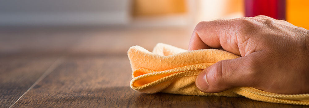 Mensch mit Lappen in der Hand, der das Parkett ölt